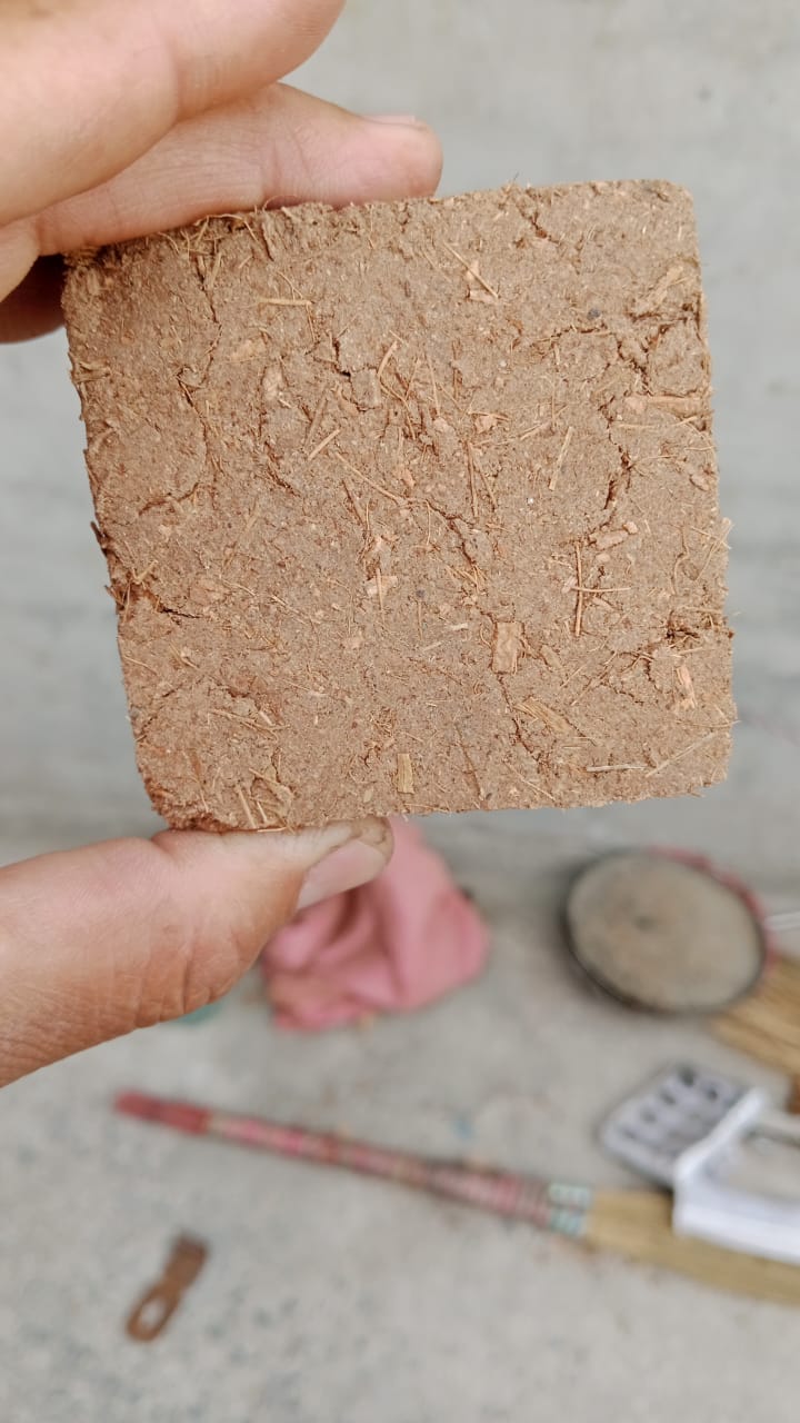 Square piece of brown material held between fingers with a blurred background