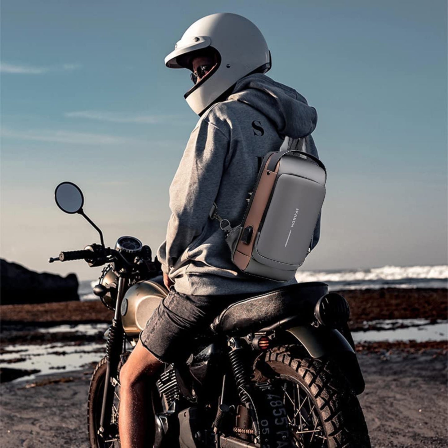 Person sitting on a motorcycle with a backpack, wearing a helmet, against a scenic background.