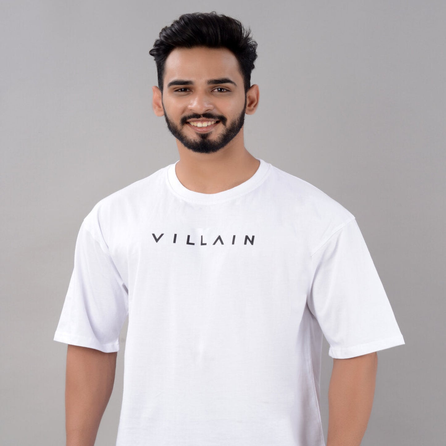 Man wearing a white t-shirt with 'VILLAIN' text on a gray background
