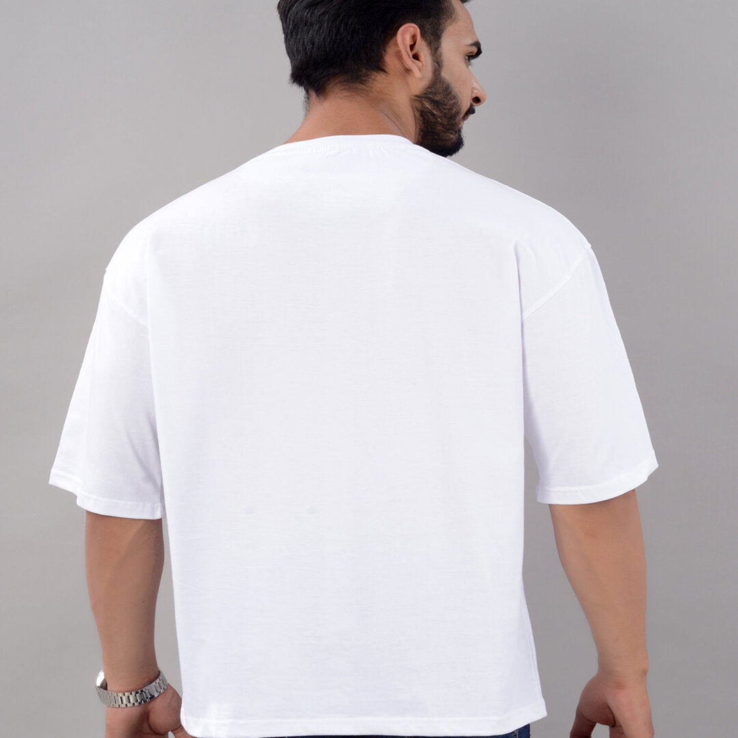 Man wearing a plain white t-shirt against a gray background