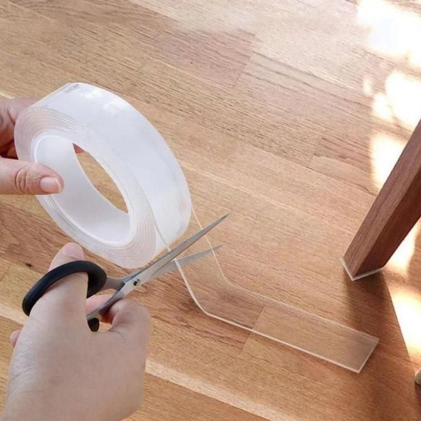 Person cutting clear tape with scissors on a wooden surface.grandsell